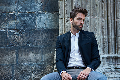 Buy stock photo Cropped shot of a handsome young businessman sitting in an urban alleyway