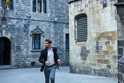 Buy stock photo Cropped shot of a handsome young businessman running through an urban alleyway