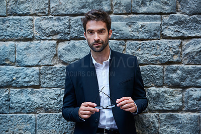 Buy stock photo Shot of a handsome young businessman in an urban alleyway