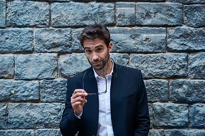 Buy stock photo Cropped portrait of a handsome young businessman standing against a brick wall in an urban alleyway