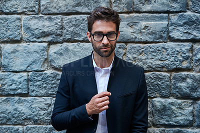 Buy stock photo Cropped portrait of a handsome young businessman standing against a brick wall in an urban alleyway