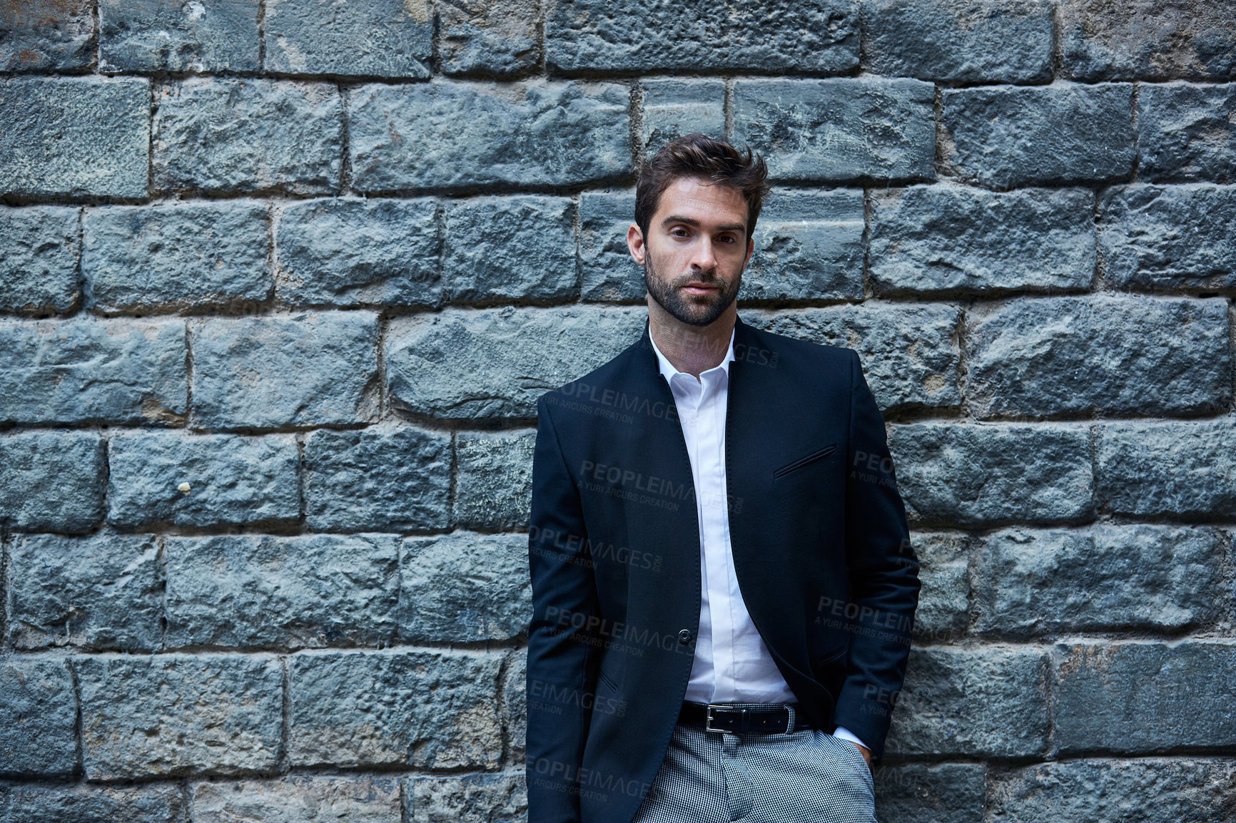 Buy stock photo Cropped portrait of a handsome young businessman standing against a brick wall in an urban alleyway