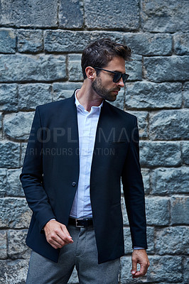 Buy stock photo Cropped shot of a handsome young businessman standing against a brick wall in an urban alleyway