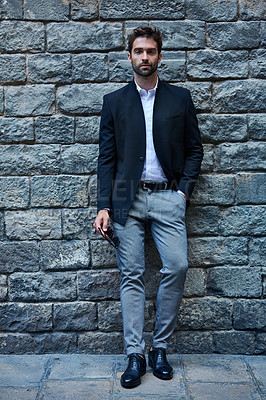 Buy stock photo Full length portrait of a handsome young businessman standing against a brick wall in an urban alleyway