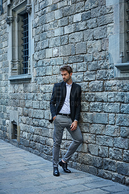 Buy stock photo Full length shot of a handsome young businessman standing against a brick wall in an urban alleyway