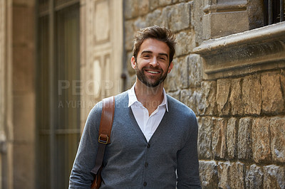 Buy stock photo Cropped portrait of a handsome young businessman walking through an urban alleyway on a sunny day