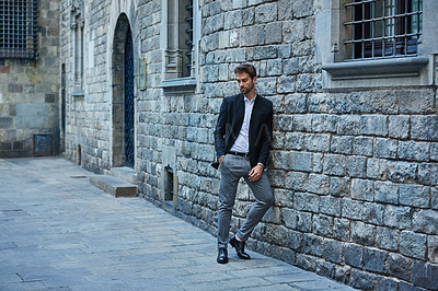 Buy stock photo Full length shot of a handsome young businessman standing against a brick wall in an urban alleyway