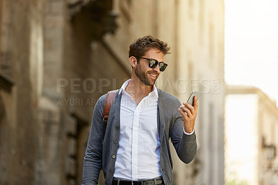 Buy stock photo Cropped shot of a handsome young businessman checking his messages while walking through an urban alleyway