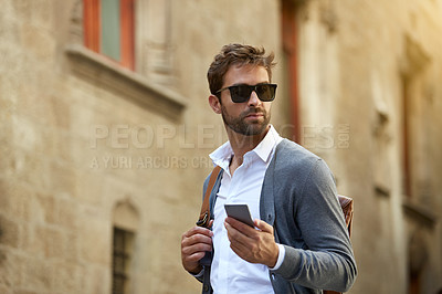 Buy stock photo Cropped shot of a handsome young businessman checking his messages while walking through an urban alleyway