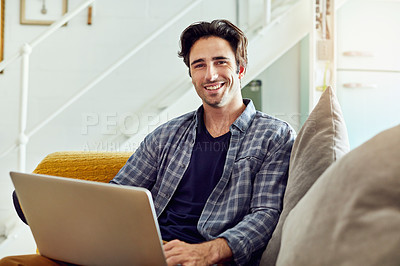 Buy stock photo Portrait of a cheerful young man working on a laptop while being seated on a couch at home