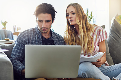 Buy stock photo Cropped shot of a young attractive couple planning their home budget together on the sofa in the living room at home
