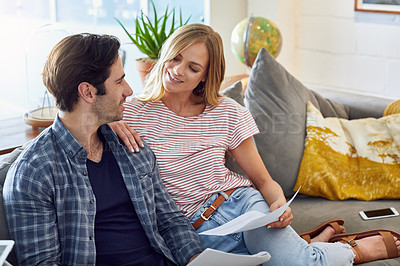 Buy stock photo Shot of a cheerful young couple working together while being seated on a couch at home