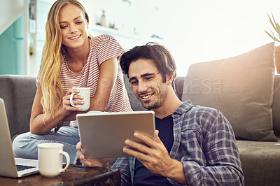 Buy stock photo Cropped shot of a young attractive couple using wireless technology at home