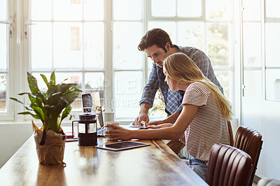 Buy stock photo Shot of a focused young couple doing paperwork together while being seated next to a table at home