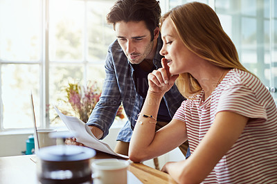 Buy stock photo Shot of a focused young couple doing paperwork together while being seated next to a table at home