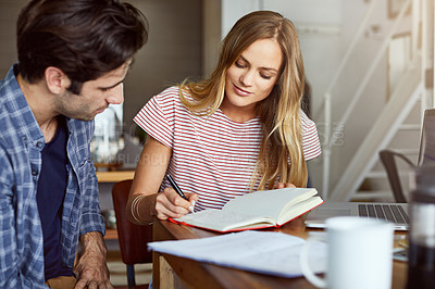 Buy stock photo Shot of a focused young couple doing paperwork together while being seated next to a table at home