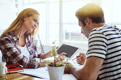 Buy stock photo Shot of a focused young couple drawing plans and choosing colors for the renovation of their house while making use of a digital tablet