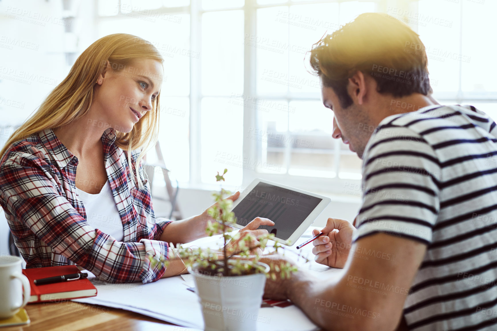 Buy stock photo Shot of a focused young couple drawing plans and choosing colors for the renovation of their house while making use of a digital tablet