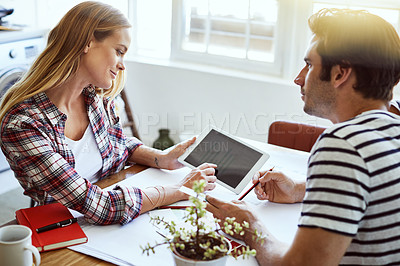 Buy stock photo Shot of a focused young couple drawing plans and choosing colors for the renovation of their house while making use of a digital tablet