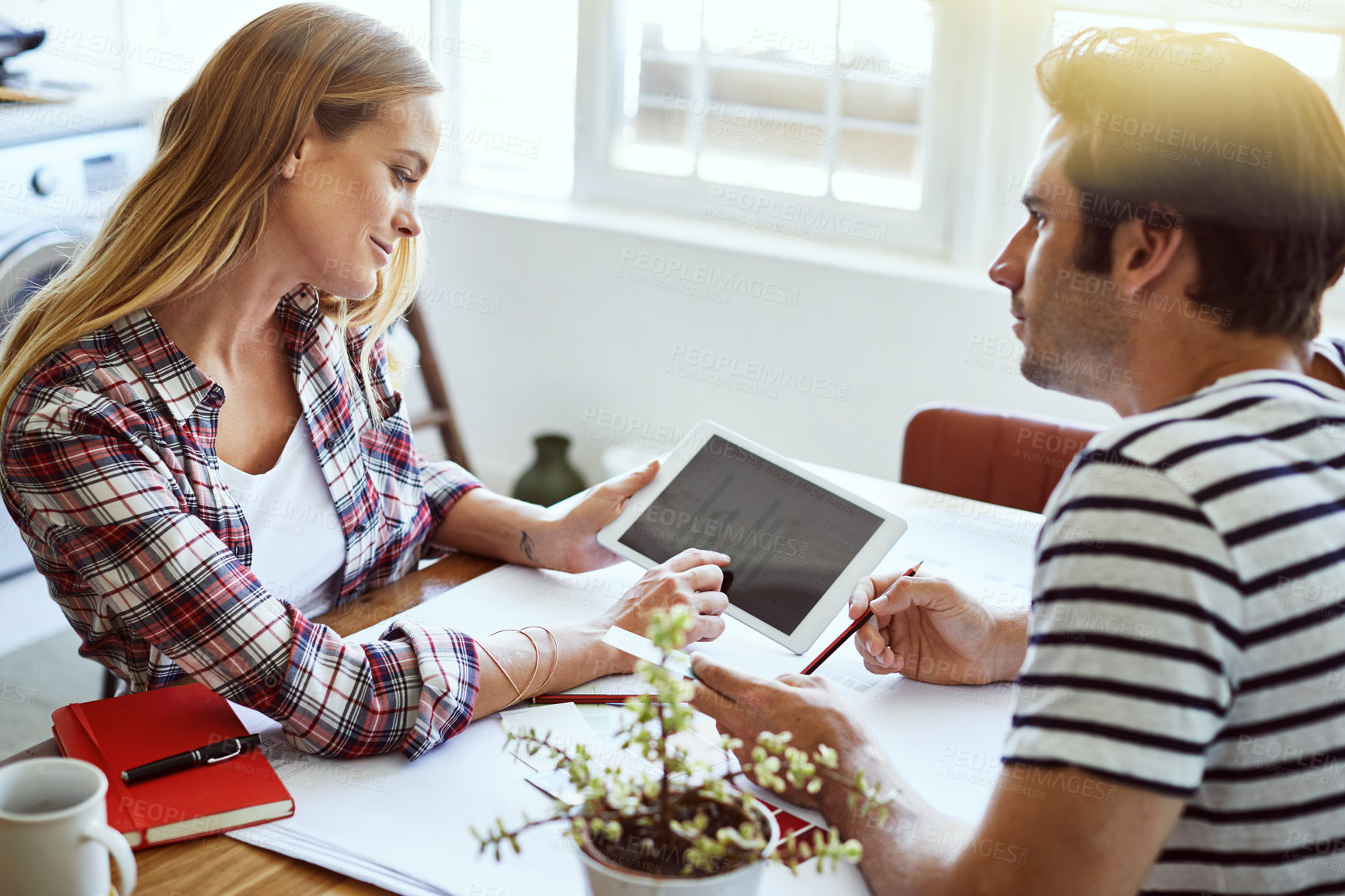 Buy stock photo Shot of a focused young couple drawing plans and choosing colors for the renovation of their house while making use of a digital tablet