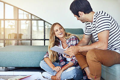 Buy stock photo Shot of a focused young couple drawing plans and choosing colors for the renovation of their house while being seated on the floor