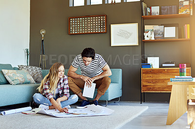 Buy stock photo Shot of a focused young couple drawing plans and choosing colors for the renovation of their house while being seated on the floor