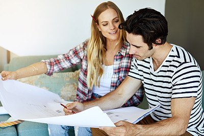 Buy stock photo Shot of a focused young couple drawing plans and choosing colors for the renovation of their house