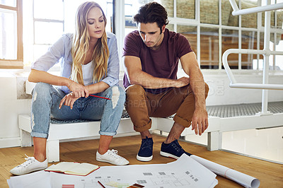 Buy stock photo Shot of a focused young couple drawing plans and choosing colors for the renovation of their house
