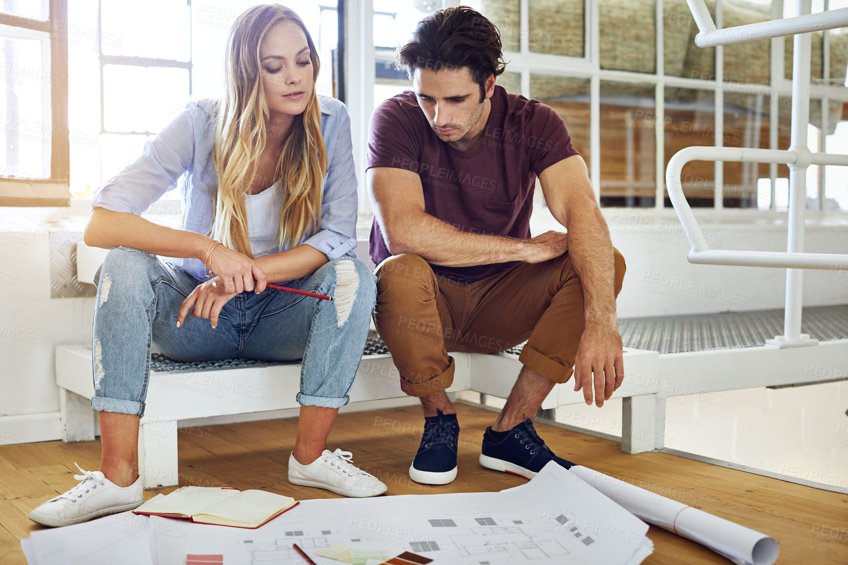 Buy stock photo Shot of a focused young couple drawing plans and choosing colors for the renovation of their house