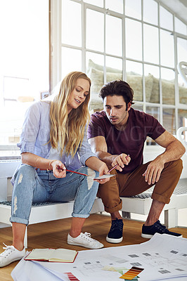 Buy stock photo Shot of a focused young couple drawing plans and choosing colors for the renovation of their house
