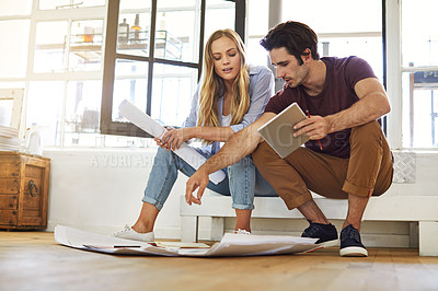 Buy stock photo Shot of a focused young couple drawing plans and choosing colors for the renovation of their house