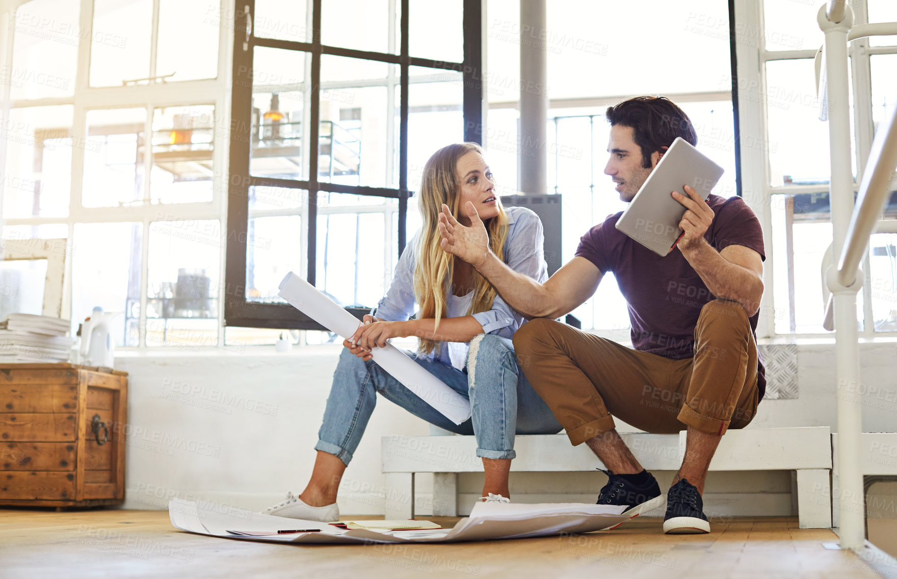 Buy stock photo Shot of a focused young couple drawing plans and choosing colors for the renovation of their house