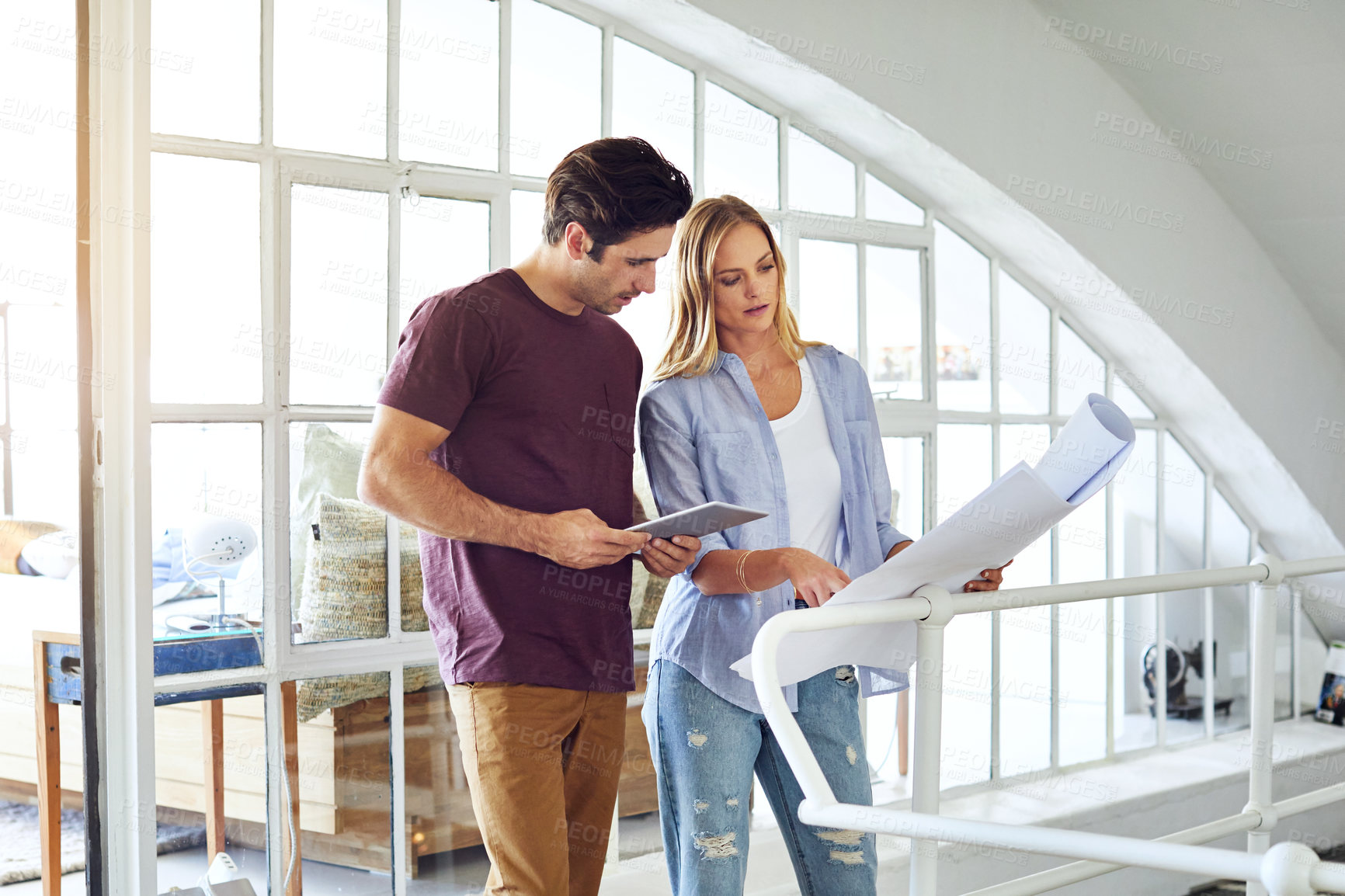 Buy stock photo Shot of a focused young couple drawing plans and choosing colors for the renovation of their house