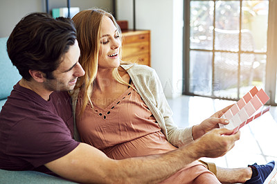 Buy stock photo Shot of a young man choosing color swatches with his pregnant wife to decide the color of the room