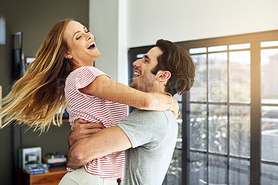 Buy stock photo Shot of a happy young man lovingly picking up his wife at home