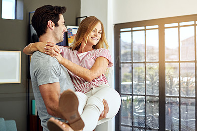 Buy stock photo Shot of a happy young man lovingly carrying his wife at home