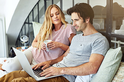 Buy stock photo Shot of a young couple using a laptop together while relaxing on the bed at home