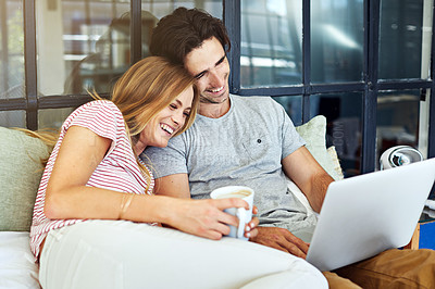Buy stock photo Shot of a young couple using a laptop together while relaxing on the bed at home