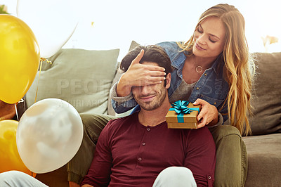 Buy stock photo Shot of a young woman giving her husband a gift at home