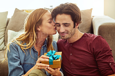 Buy stock photo Shot of a young woman giving her husband a gift at home