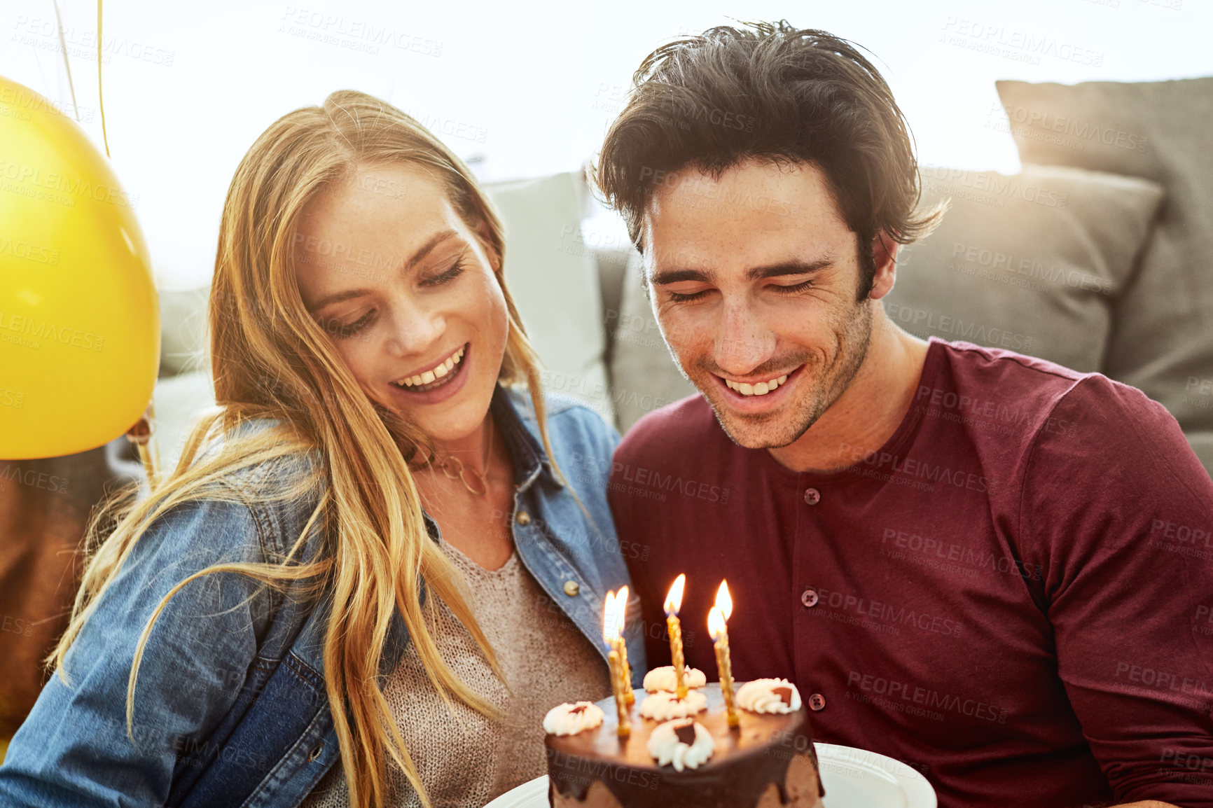 Buy stock photo Shot of a young couple having cake while celebrating a birthday at home