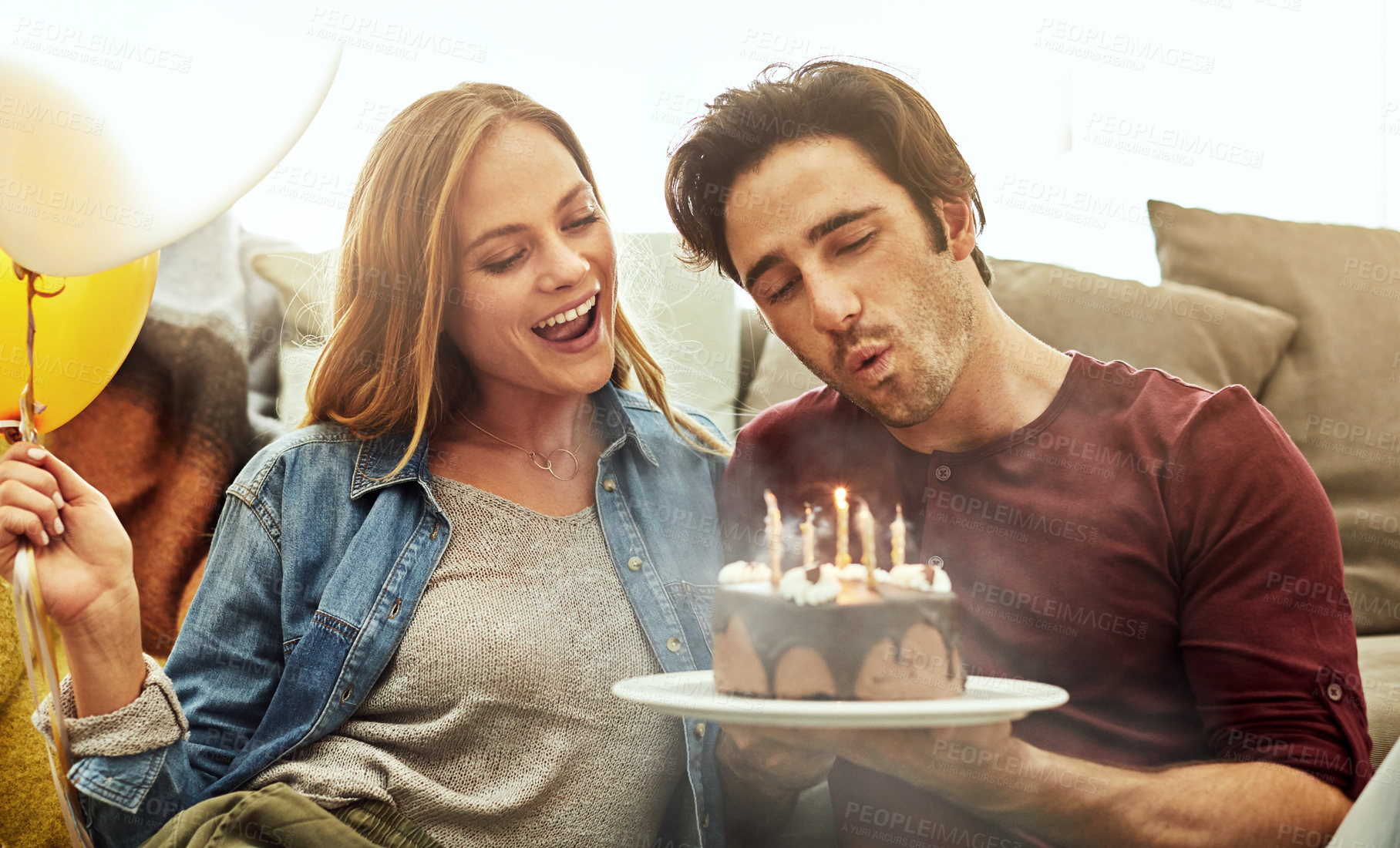 Buy stock photo Shot of a young couple having cake while celebrating a birthday at home