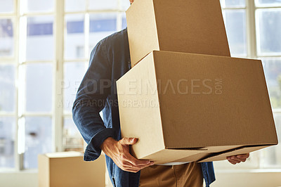 Buy stock photo Cropped shot of a young man carrying boxes while moving into his new home