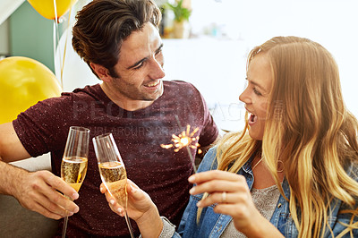 Buy stock photo Shot of a young couple toasting with champagne to celebrate at home