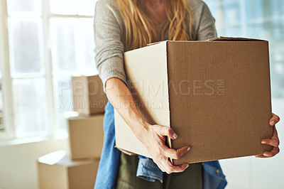Buy stock photo Cropped shot of a young woman carrying boxes while moving into her new home