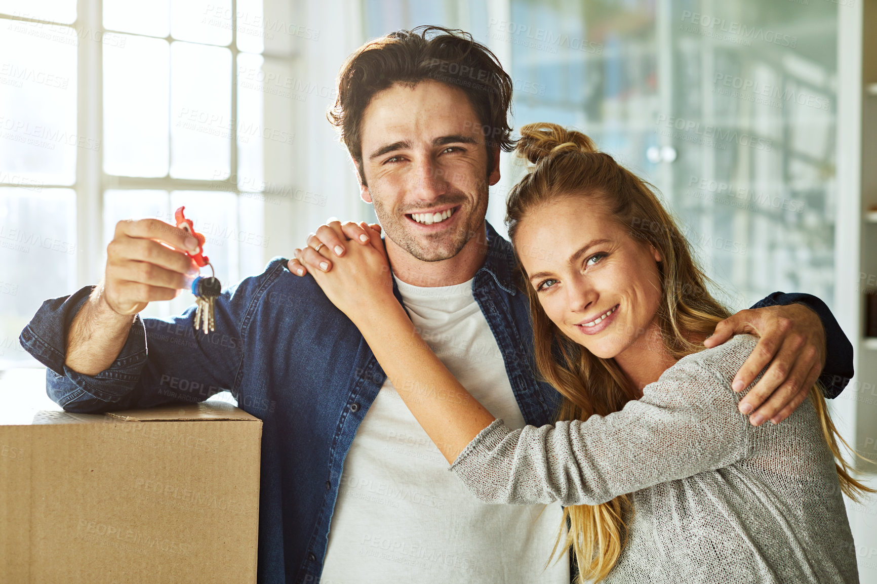 Buy stock photo Shot of an affectionate young couple holding up the keys to their new home