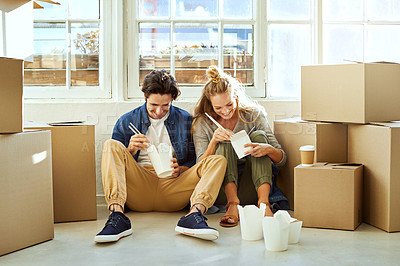 Buy stock photo Shot of a young couple eating takeout while taking a break moving into their new home