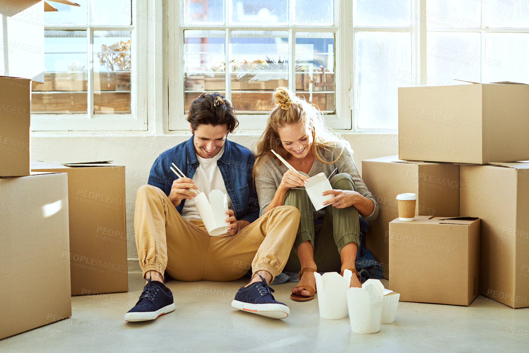 Buy stock photo Shot of a young couple eating takeout while taking a break moving into their new home