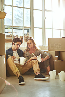 Buy stock photo Shot of a young couple eating takeout while taking a break moving into their new home