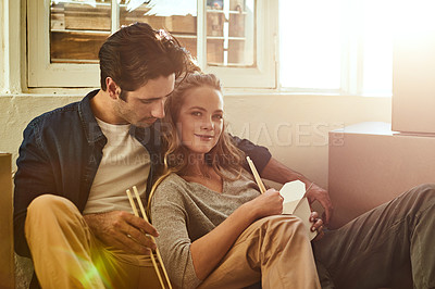 Buy stock photo Shot of a young couple eating takeout while taking a break moving into their new home